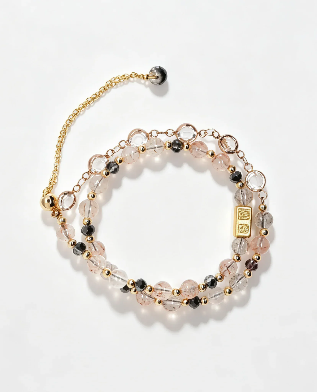 Layered crystal bracelet with pink, clear, and black beads, gold accents, and healing gemstone charm for positive energy