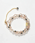 Layered crystal bracelet with pink, clear, and black beads, gold accents, and healing gemstone charm for positive energy