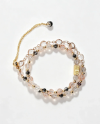 Layered crystal bracelet with pink, clear, and black beads, gold accents, and healing gemstone charm for positive energy