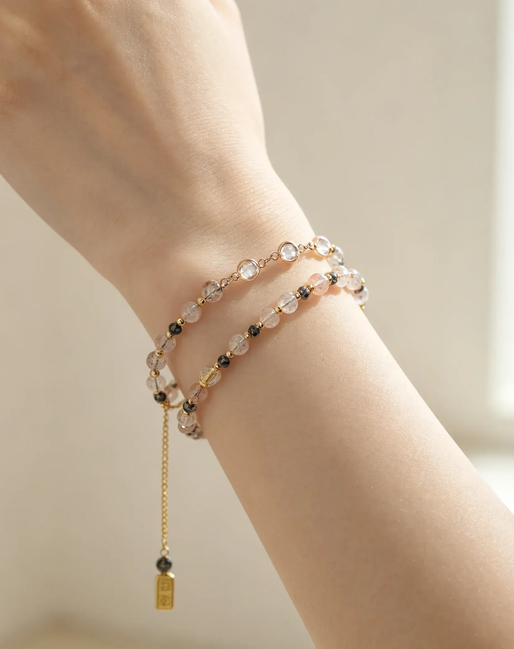 Hand wearing layered natural crystal bracelets with gold accents and healing gemstones for positive energy