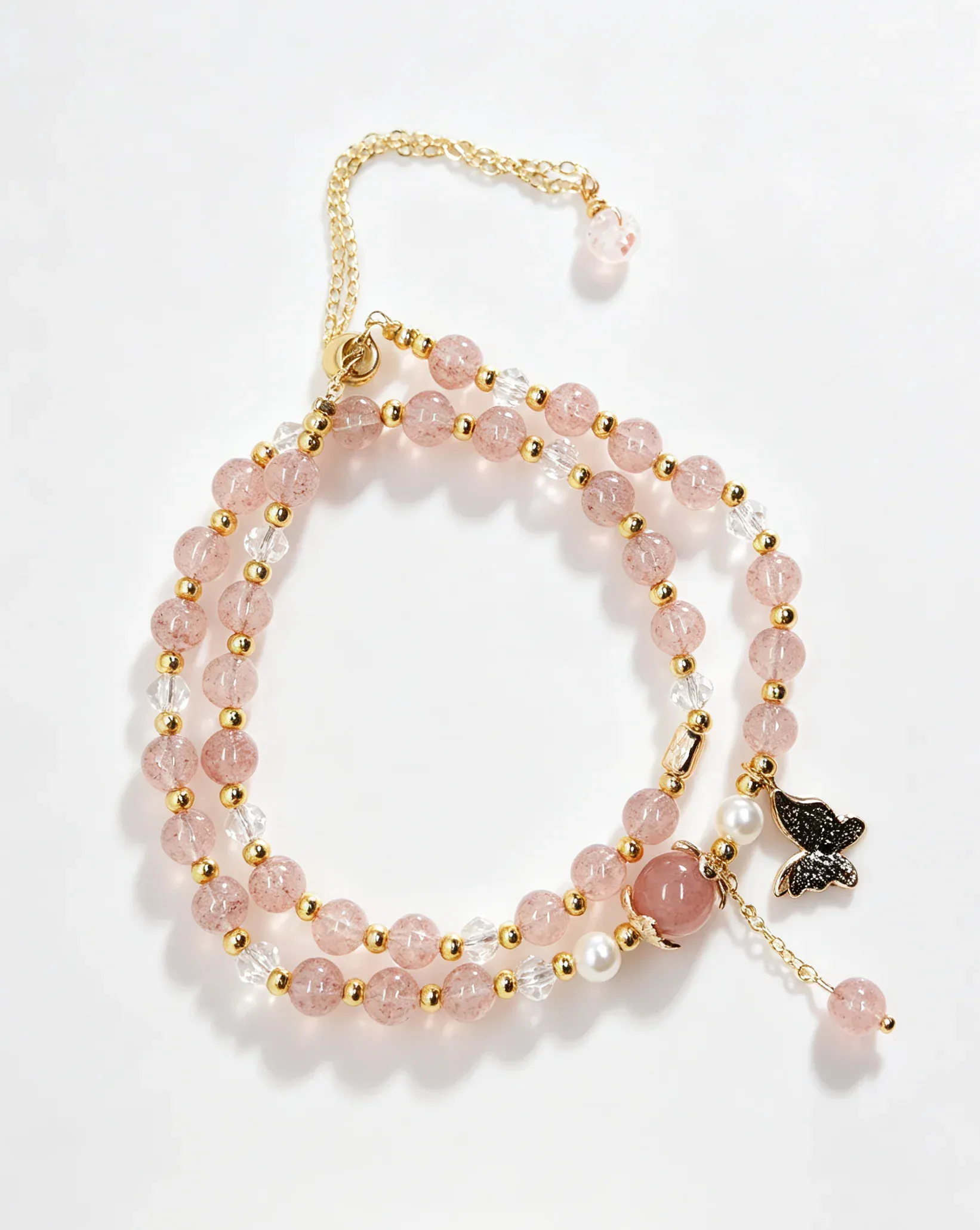 Pink crystal bracelet with gold beads, clear accents, and black butterfly charm for positive energy