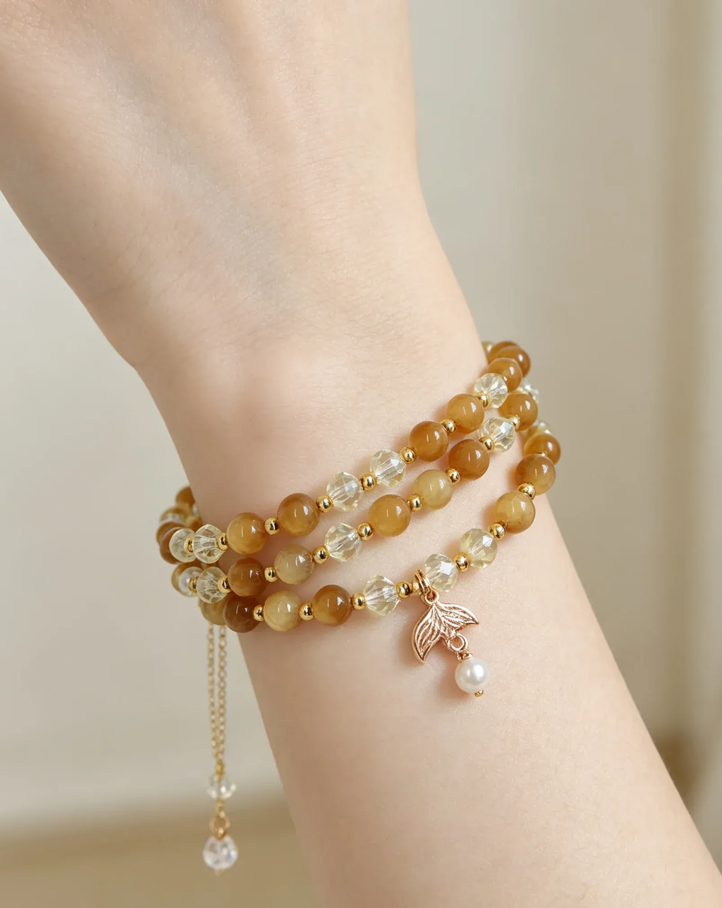 Layered natural crystal bracelet with gold beads, leaf charm, and pearl accent for positive energy