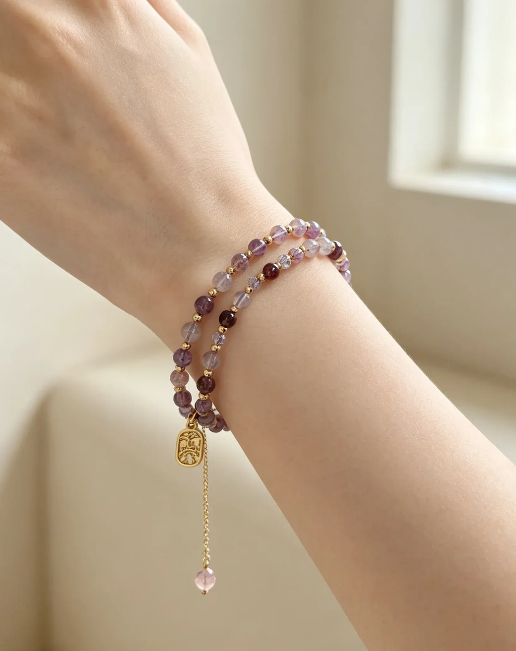 Purple crystal bracelet with gold charm on wrist, natural gemstone healing accessory for women