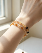 Hand wearing layered natural crystal bracelets with amber and gold beads, perfect for healing energy and style.