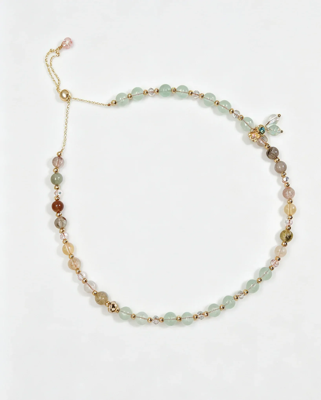 Handcrafted natural crystal bracelet with green, pink, and gold beads, featuring a dragonfly charm for positive energy.