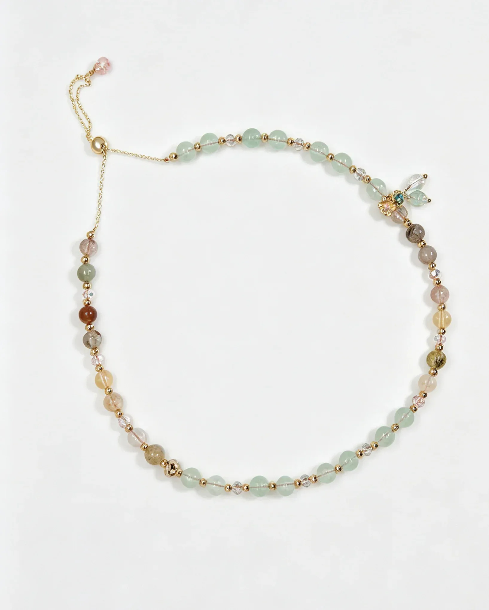 Handcrafted natural crystal bracelet with green, pink, and gold beads, featuring a dragonfly charm for positive energy.