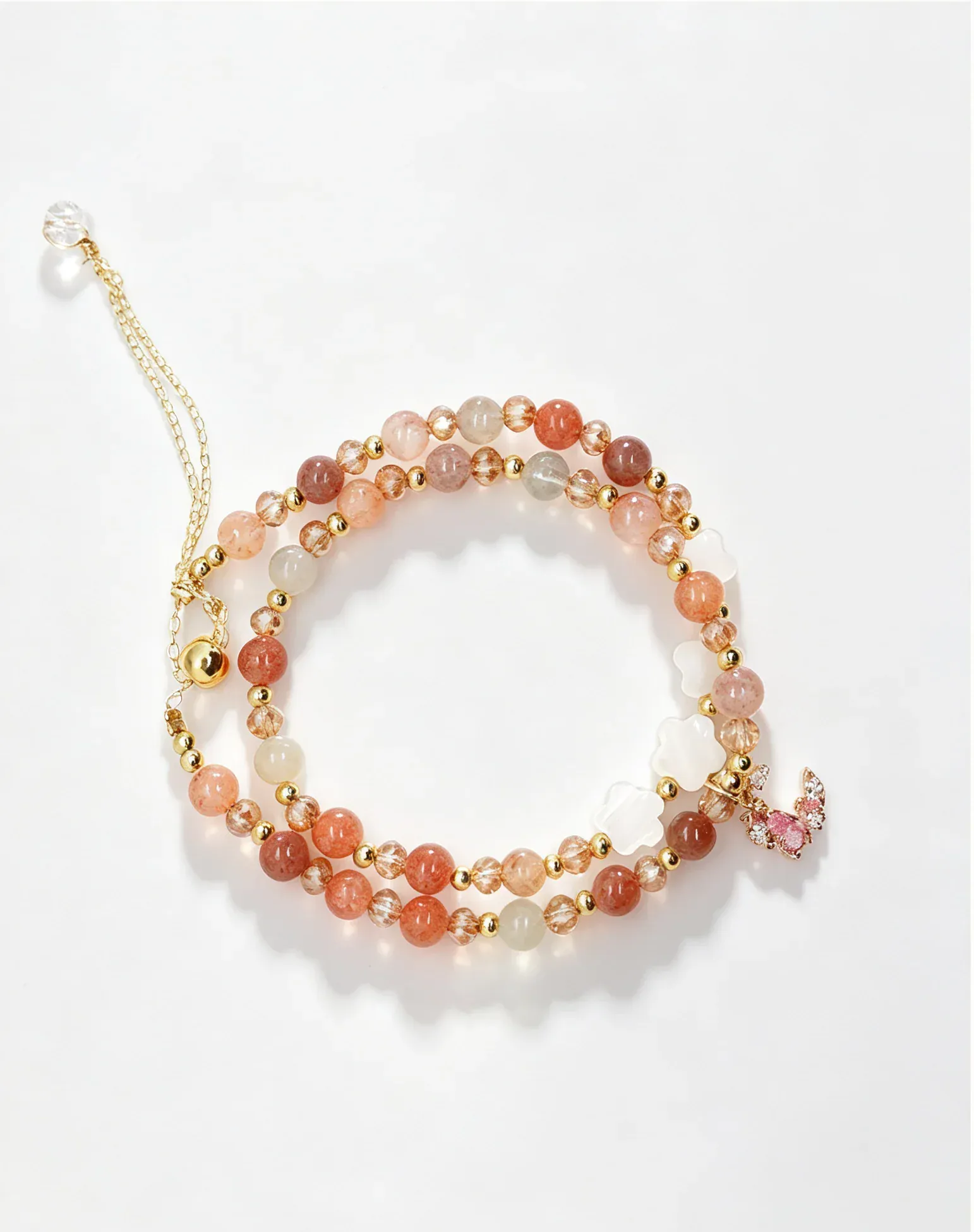 Handcrafted natural crystal bracelet with pink, peach, and gold beads, featuring a delicate butterfly charm for positive energy.