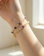 Hand wearing natural crystal bracelet with purple and gold beads, healing gemstone accessory for women