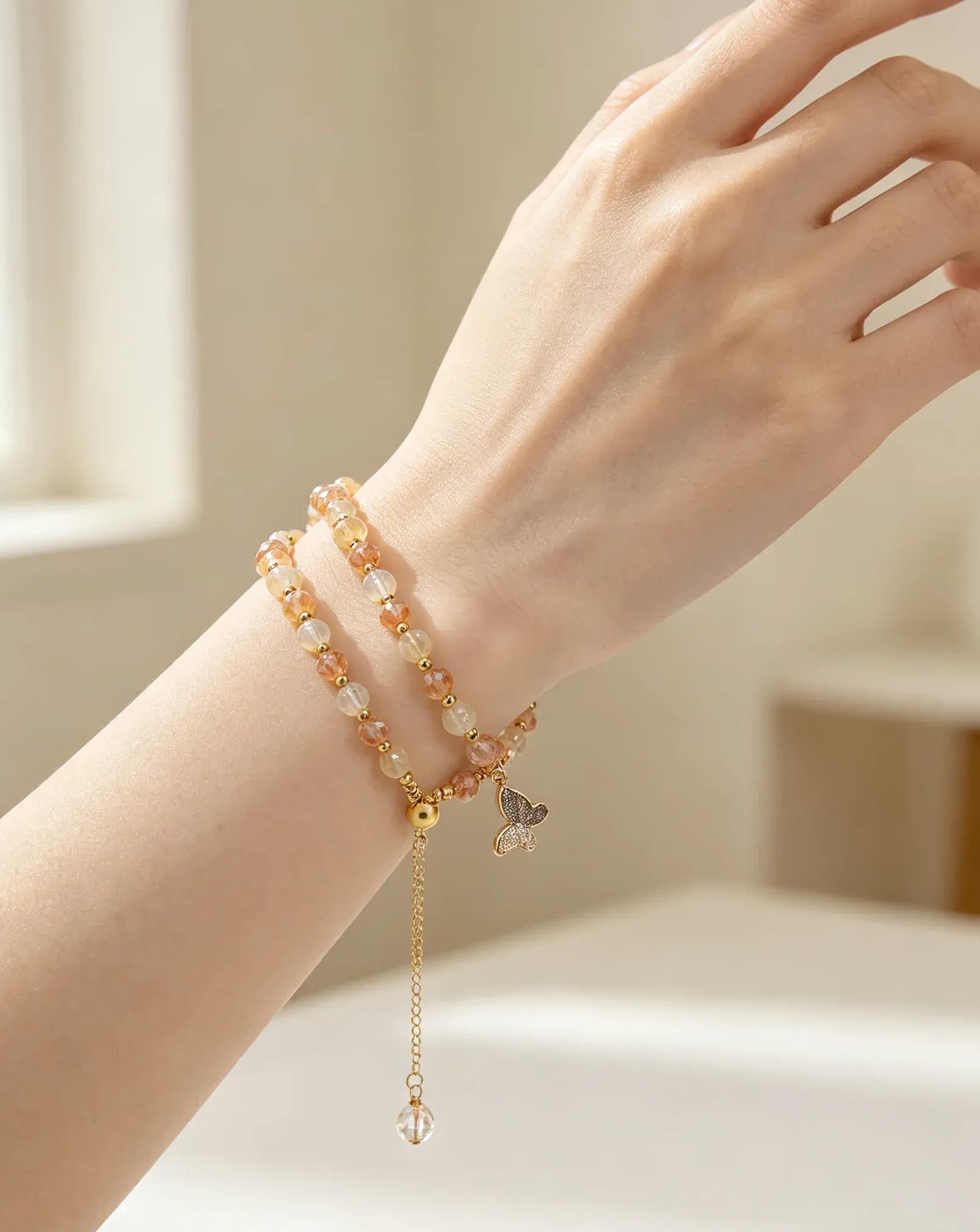 Hand wearing natural crystal bracelet with butterfly charm, healing gemstone accessory for women