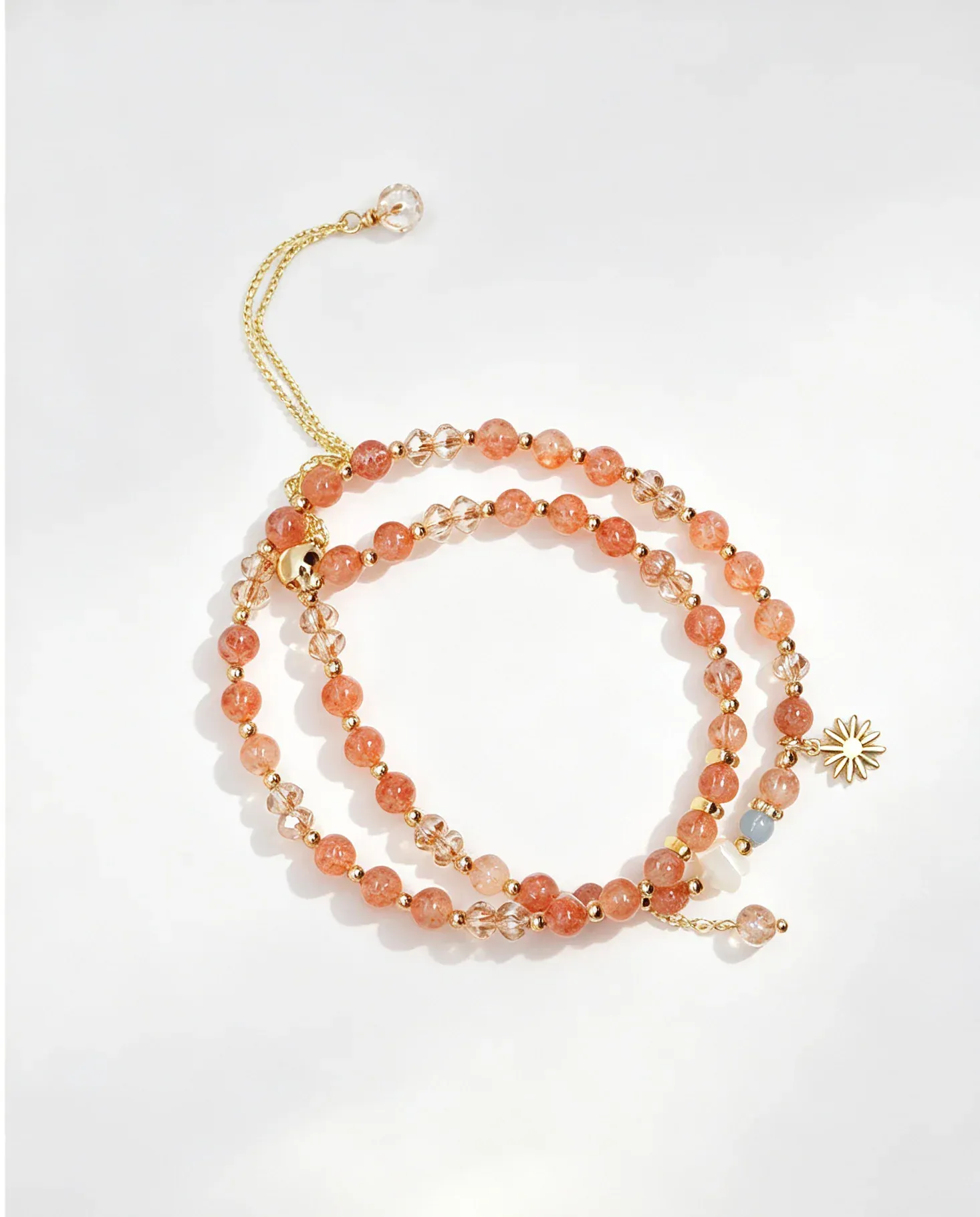 Handcrafted natural crystal bracelet with peach beads, gold chain, and sun charm for positive energy