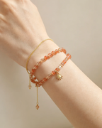 Hand wearing layered natural crystal bracelets with sun charm, healing gemstone accessories for women
