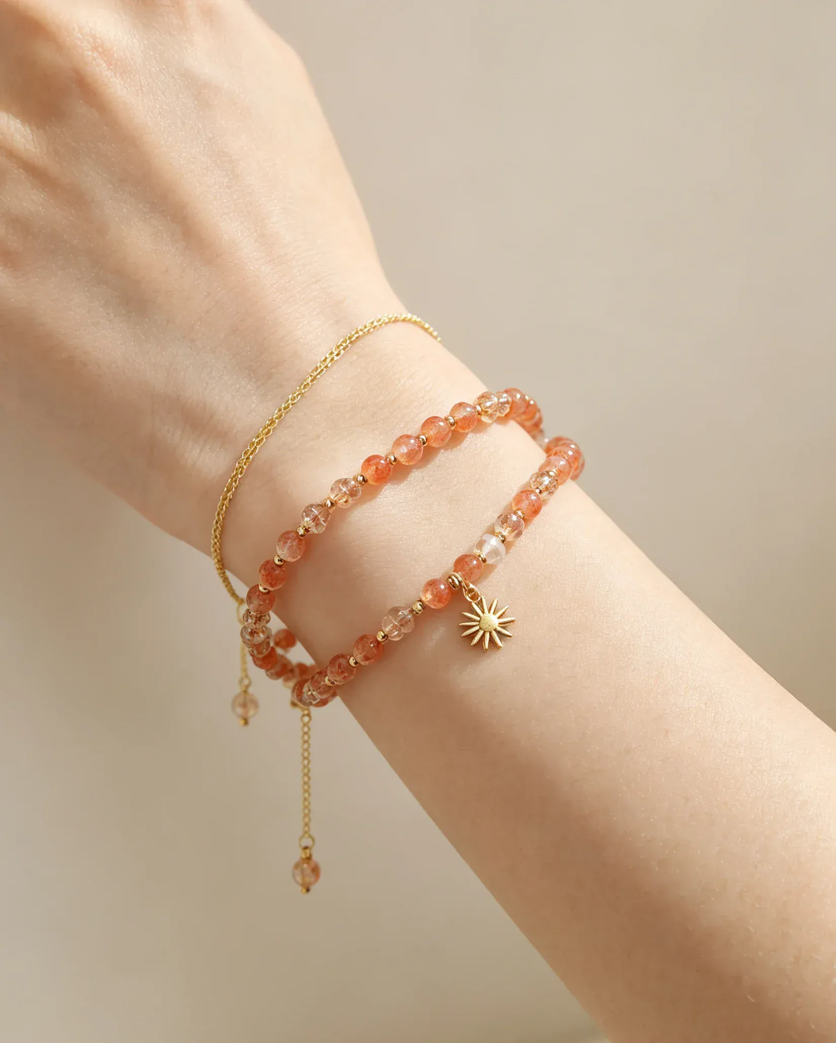 Hand wearing layered natural crystal bracelets with sun charm, healing gemstone accessories for women